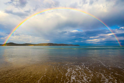 Scenic view of rainbow over sea against sky