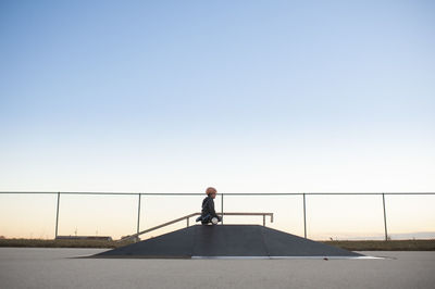 Young boy on top of ramp on hover board at skate park against blue sky