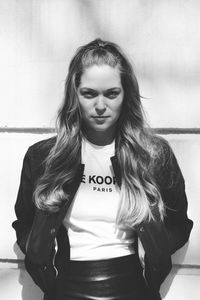 Portrait of young woman standing against wall