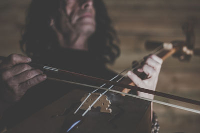 Midsection of mature man playing musical instrument at home