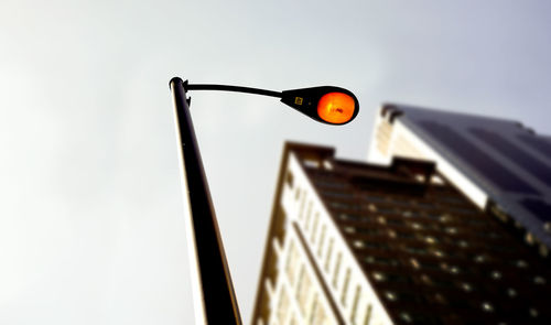 Low angle view of illuminated street light against sky in city during sunset