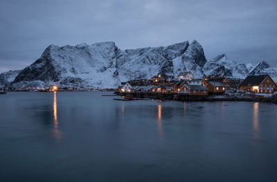 View of lake and town against mountains during winter