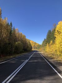 Road amidst trees against clear sky