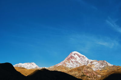 Mount kazbek and the silhouette of the gergeti trinity church in the rays of the morning sun