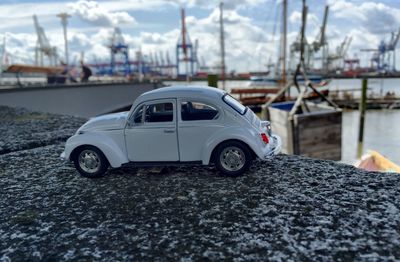Close-up of toy car on retaining wall against harbor