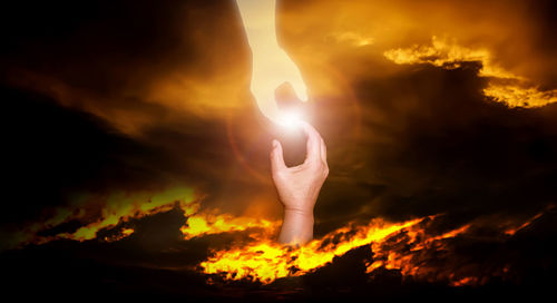 Low angle view of hands against sky during sunset