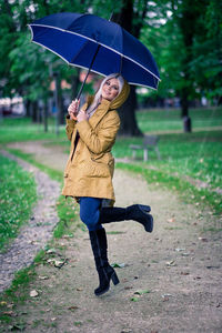 Full length of woman with umbrella standing in rain
