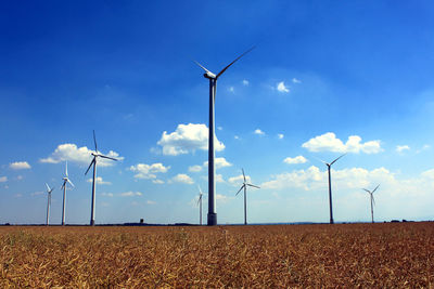 Wind turbines on field against sky