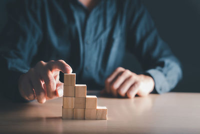 Midsection of man playing with toy blocks on table