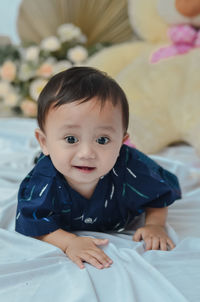 Portrait of cute baby boy lying on bed at home