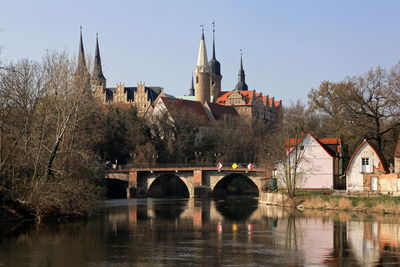 Arch bridge over river by buildings against sky