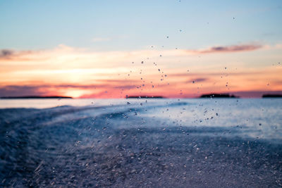 Close-up of water drops on sea against sky during sunset