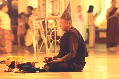 Side view of monk meditating while sitting on floor