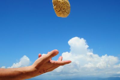 Low angle view of man hand against blue sky