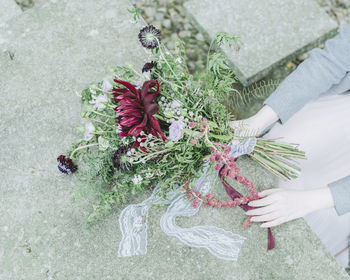 Cropped image of bridesmaid holding flower bouquet over retaining wall