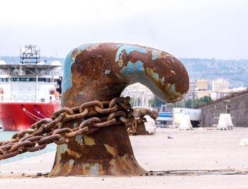 Close-up of rusty chain against sky in city