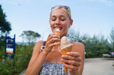 Woman licking ice cream on street against clear sky