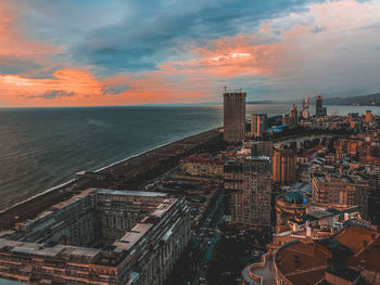 High angle view of buildings by sea against sky during sunset