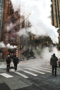 People amidst smoke on city street
