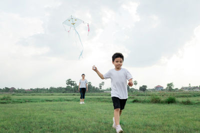 Full length of father and daughter on field against sky