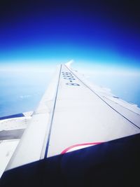 Close-up of airplane wing against blue sky