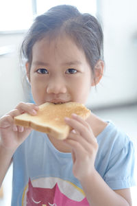 Portrait of girl eating bread at home