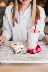 Midsection of woman holding ice cream on table