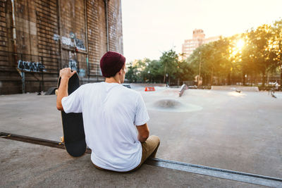 Rear view of man sitting in city against sky