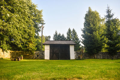 Built structure on field by trees against sky