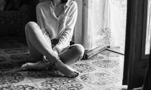 Low section of woman sitting on floor at home