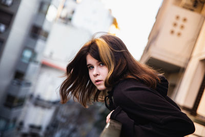 Portrait of beautiful young woman standing against blurred background