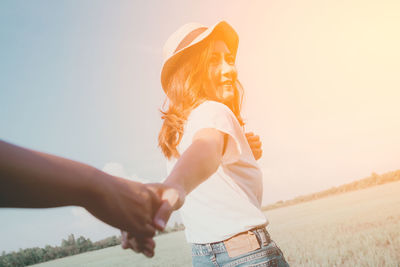 Cropped image of man holding woman hand on field at park