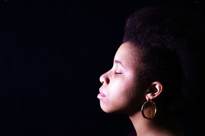 Close-up of young woman against black background