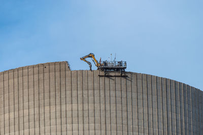 Demolition of the atomic chimney. remote controlled excavator with shears works from above.