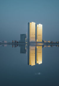 Reflection of buildings in sea against clear sky