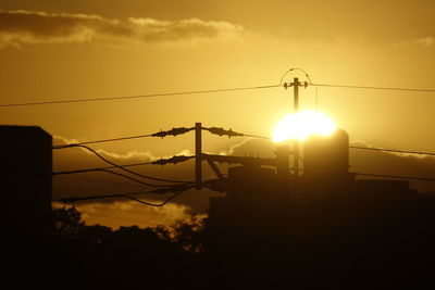 Silhouette electricity pylon against sky during sunset