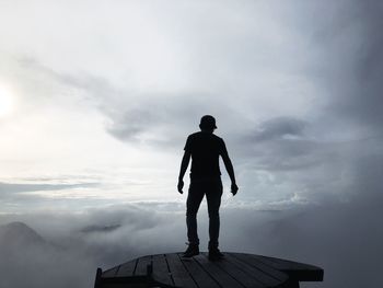 Rear view of silhouette man standing on mountain against sky