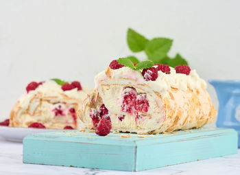 Baked meringue roll with cream and fresh red raspberry, white background