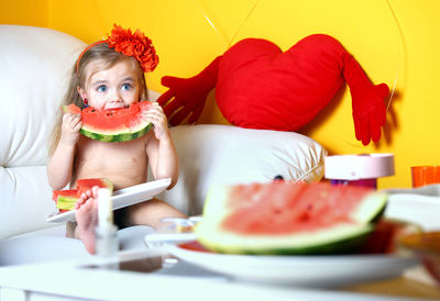 A 3 year old girl eats a watermelon.