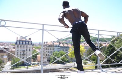 Full length of man jumping in city against sky