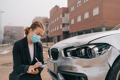 Midsection of young woman photographing car