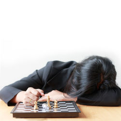 Woman sleeping by chess board at table