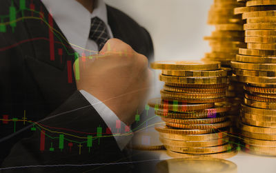 Double exposure of stacked coins and businessman at desk