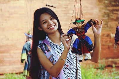 Portrait of smiling young woman holding puppet on field