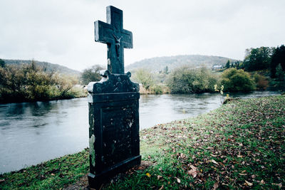 Cross on lake against sky