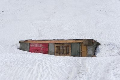 House on snow covered field by building