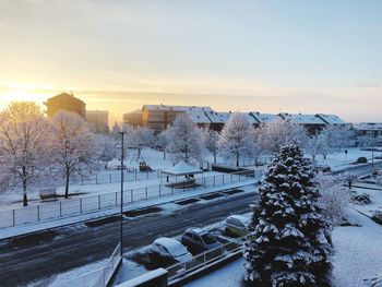 High angle view of snow covered city against sky during sunset