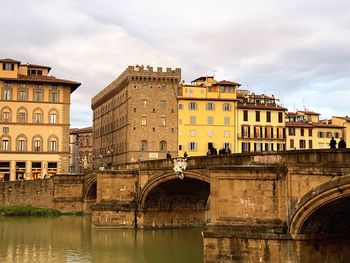 Arch bridge over river against buildings in city