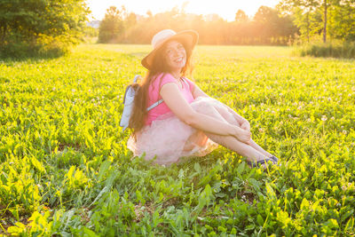 Full length of smiling young woman on field