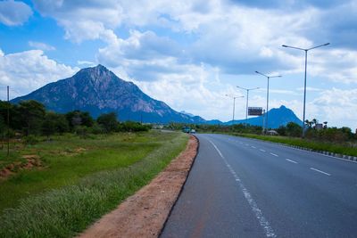 Road by mountains against sky